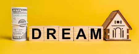 DREAM with house miniature model and money on a yellow background. The concept of business, finance, credit, tax , real estate, home, housingの写真素材