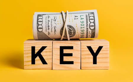 KEY with money on a yellow background. The concept of business, finance, credit, income, savings, investments, exchange, taxの写真素材