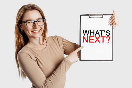 what is next. Beautiful young business woman wearing glasses holds a clipboard with mock up space isolated on gray backgroundの写真素材
