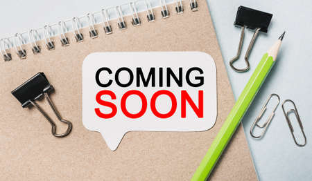 Text COMING SOON on a white sticker with office stationery background. Flat lay on business, finance and development conceptの写真素材
