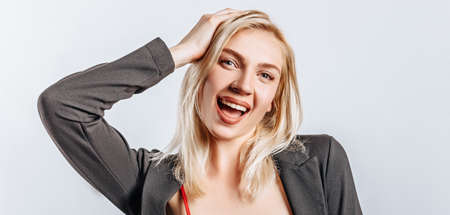 Hey smile at you. The blonde girl is happy and holds her hand to her head. A beautiful woman is pleased with an excellent business proposal. Nose piercing, rhinestone on the tooth. Isolated backgroundの写真素材