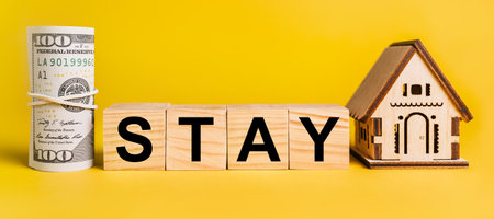 STAY with house miniature model and money on a yellow background. The concept of business, finance, credit, tax , real estate, home, housingの写真素材