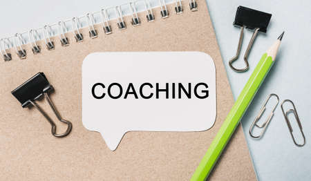 Text COACHING on a white sticker with office stationery background. Flat lay on business, finance and development conceptの写真素材