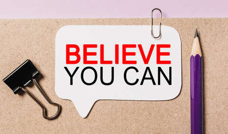 Text Believe you can on a white sticker with office stationery background. Flat lay on business, finance and development conceptの写真素材