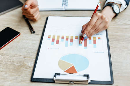 Business woman checks charts and refreshes financial progress. The girl analyzes the business model in the workplace.の写真素材