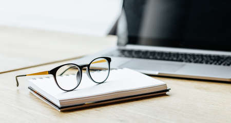 Glasses at the workplace in the office near the laptop and notepad. Business hoursの写真素材