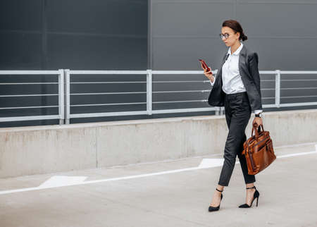 A business woman checks the time in the city during a working day waiting for a meeting. Discipline and timing. An employee goes towards a corporate meeting.の写真素材