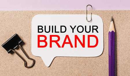Text Build Your Brand on a white sticker with office stationery background. Flat lay on business, finance and development conceptの写真素材