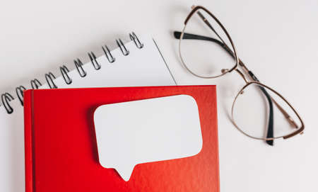 Red notepad, white sticker and glasses on the desk. Mock up in copy space office background. It is important not to forget the noteの写真素材