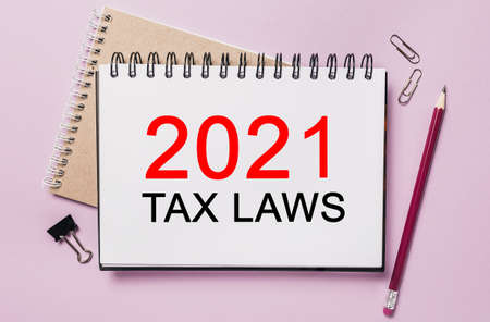 Text 2021 tax laws on a white sticker with office stationery background. Flat lay on business, finance and development conceptの写真素材