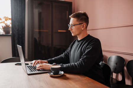 Handsome man working on laptop in the workplace. Businessman at work table with coffeeの写真素材