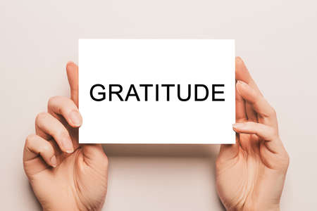 Female hands hold card paper with text Gratitude on a yellow background. Business and finance conceptの写真素材