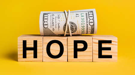 HOPE with money on a yellow background. The concept of business, finance, credit, income, savings, investments, exchange, taxの写真素材