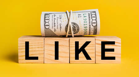 LIKE with money on a yellow background. The concept of business, finance, credit, income, savings, investments, exchange, taxの写真素材