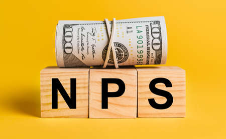 NPS with money on a yellow background. The concept of business, finance, credit, income, savings, investments, exchange, taxの写真素材
