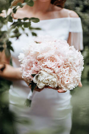 Girl bride holding a wedding bouquet of flowersの写真素材