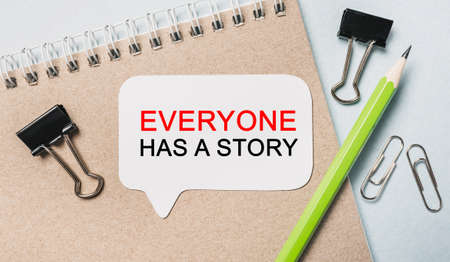 Text Everyone has a story on a white sticker with office stationery background. Flat lay on business, finance and development conceptの写真素材
