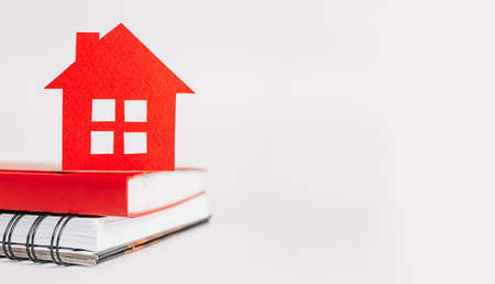 Sweet home. Estimating and paying house tax. Mock up with red house, notepad and sticker in copy space white backgroundの写真素材