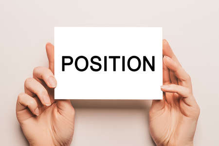 Female hands hold card paper with text POSITION on a yellow background. Business and finance conceptの写真素材