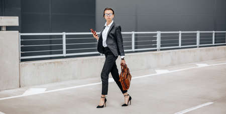 A business woman checks the time in the city during a working day waiting for a meeting. Discipline and timing. An employee goes towards a corporate meeting.の写真素材