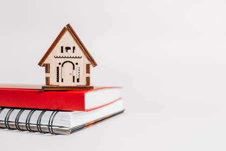 Sweet home. Estimating and paying house tax. Mock up with red house, notepad and sticker in copy space white backgroundの写真素材