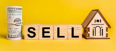 SELL with house miniature model and money on a yellow background. The concept of business, finance, credit, tax , real estate, home, housingの写真素材