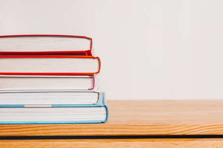 A stack of books on wooden table. Mock up with education and reading concept. Literature for...