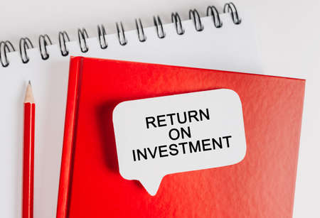 Text Return on Investment on a white sticker with office stationery background. Flat lay on business, finance and development conceptの写真素材