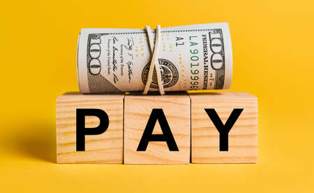 PAY with money on a yellow background. The concept of business, finance, credit, income, savings, investments, exchange, taxの写真素材