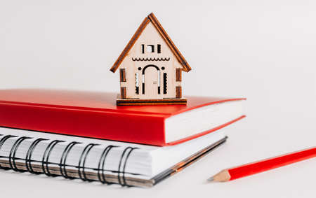 Sweet home. Estimating and paying house tax. Mock up with red house, notepad and sticker in copy space white backgroundの写真素材