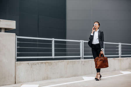 A business woman checks the time in the city during a working day waiting for a meeting. Discipline and timing. An employee goes towards a corporate meeting.の写真素材