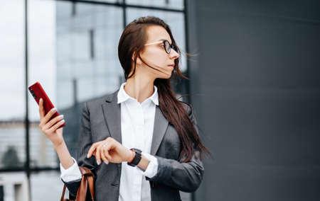 A business woman checks the time in the city during a working day waiting for a meeting. Discipline and timing. An employee goes towards a corporate meeting.の写真素材