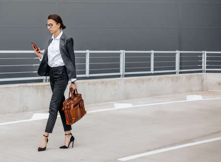 A business woman checks the time in the city during a working day waiting for a meeting. Discipline and timing. An employee goes towards a corporate meeting.の写真素材