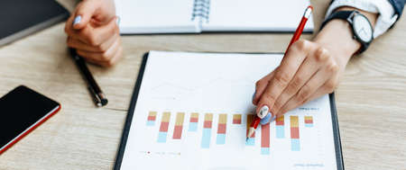 Business woman checks charts and refreshes financial progress. The girl analyzes the business model in the workplace.の写真素材