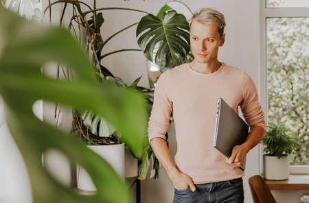 Man businessman with laptop in workspace in eco cafe with plantsの写真素材