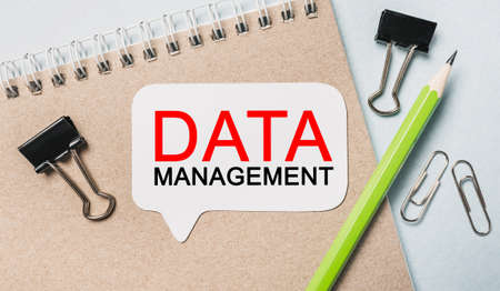 Text DATA MANAGEMENT on a white sticker with office stationery background. Flat lay on business, finance and development conceptの写真素材