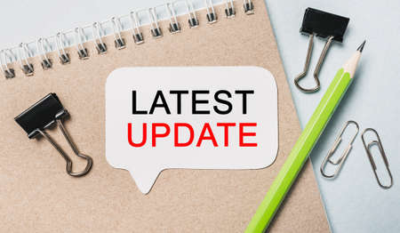 Text Latest Update on a white sticker with office stationery background. Flat lay on business, finance and development conceptの写真素材