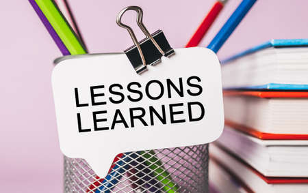 Text LESSONS LEARNED on a white sticker with office stationery background. Flat lay on business, finance and development conceptの写真素材