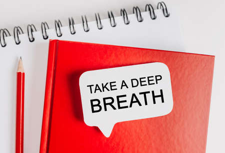 Text Take a deep breath on a white sticker with office stationery background. Flat lay on business, finance and development conceptの写真素材