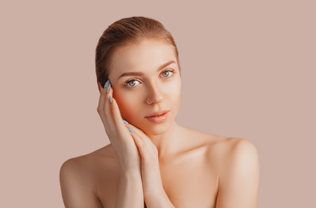 Beautiful sensual young girl with clean skin on a beige background with a mockup. Topless woman in a towel. The concept of spa treatments, natural beauty and care, youth, cream and mask, freshnessの写真素材