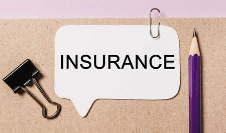 Text INSURANCE on a white sticker with office stationery background. Flat lay on business, finance and development conceptの写真素材