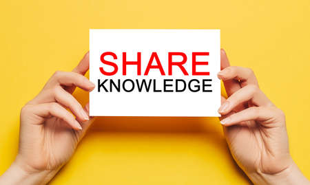 Female hands hold card paper with text SHARE KNOWLEDGE on a yellow background. Business and finance conceptの写真素材
