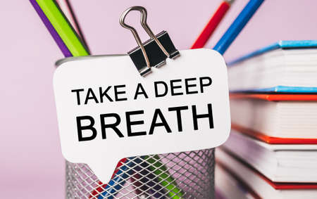 Text Take a deep breath on a white sticker with office stationery background. Flat lay on business, finance and development conceptの写真素材