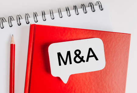 Text M and A on a white sticker with office stationery background. Flat lay on business, finance and development conceptの写真素材