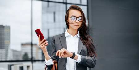A business woman checks the time in the city during a working day waiting for a meeting. Discipline and timing. An employee goes towards a corporate meeting.の写真素材