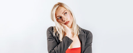 The woman thought about the choice and furrowed her eyebrows. Young beautiful blonde girl holds a hand to the face thinks and makes a decision. Place for advertising. What to chooseの写真素材