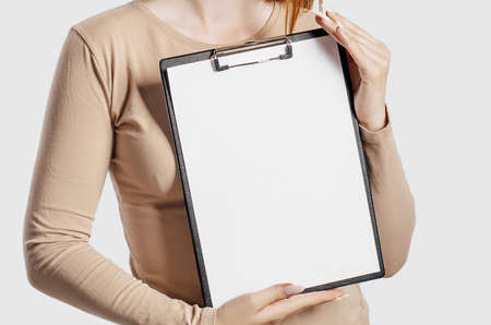 Young business woman holds a clipboard with mock up blank space isolated on gray background. Achieving career wealth business concept. Online learning coverの写真素材