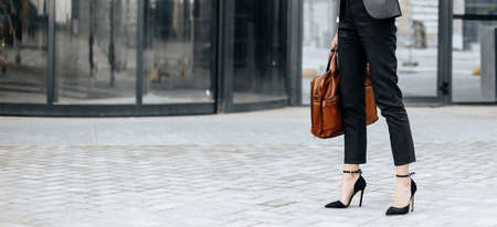 A business woman checks the time in the city during a working day waiting for a meeting. Discipline and timing. An employee goes towards a corporate meeting.の写真素材