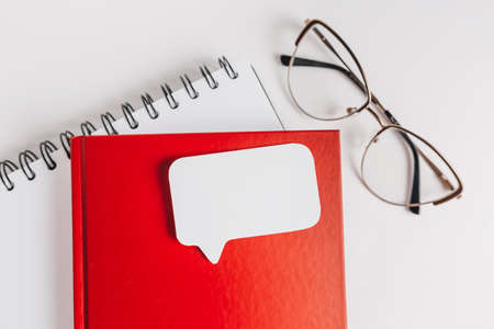 Red notepad, white sticker and glasses on the desk. Mock up in copy space office background. It is important not to forget the noteの写真素材