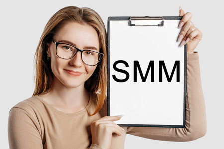 smm Beautiful young business woman wearing glasses holds a clipboard with mock up space isolated on gray backgroundの写真素材
